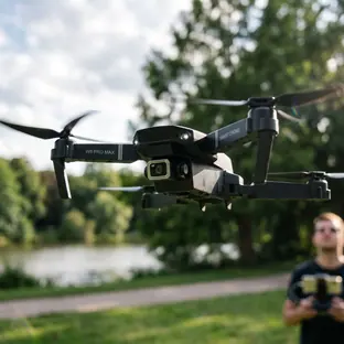 Imagen ilustrativa: dron plegable con cámara 4K en vuelo junto a un lago, con su piloto al fondo
